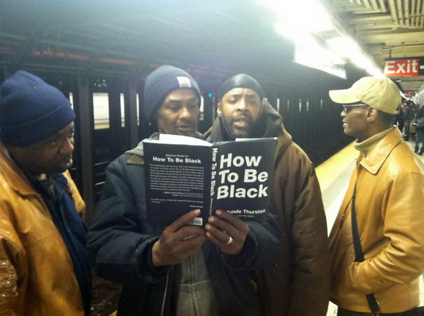 ผู้ชายผิวสีกลุ่มนี้กำลังอ่าน "วิธีการเป็นคนผิวสี"